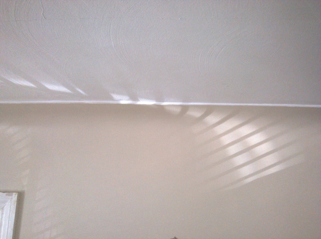 photo of ceiling and wall with shadows from window blinds in parallel lines